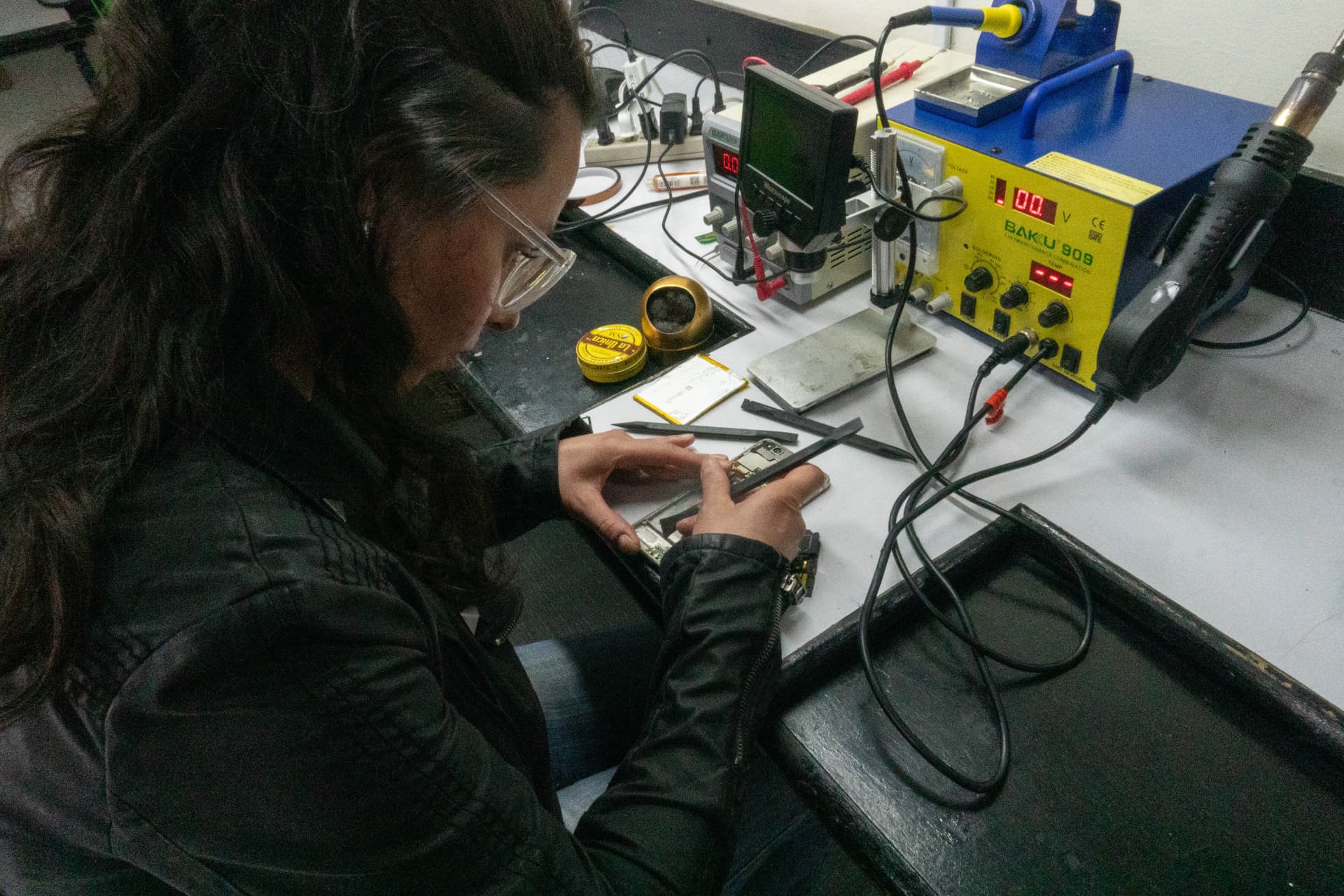 Estudiante con gafas de protección reparando celular